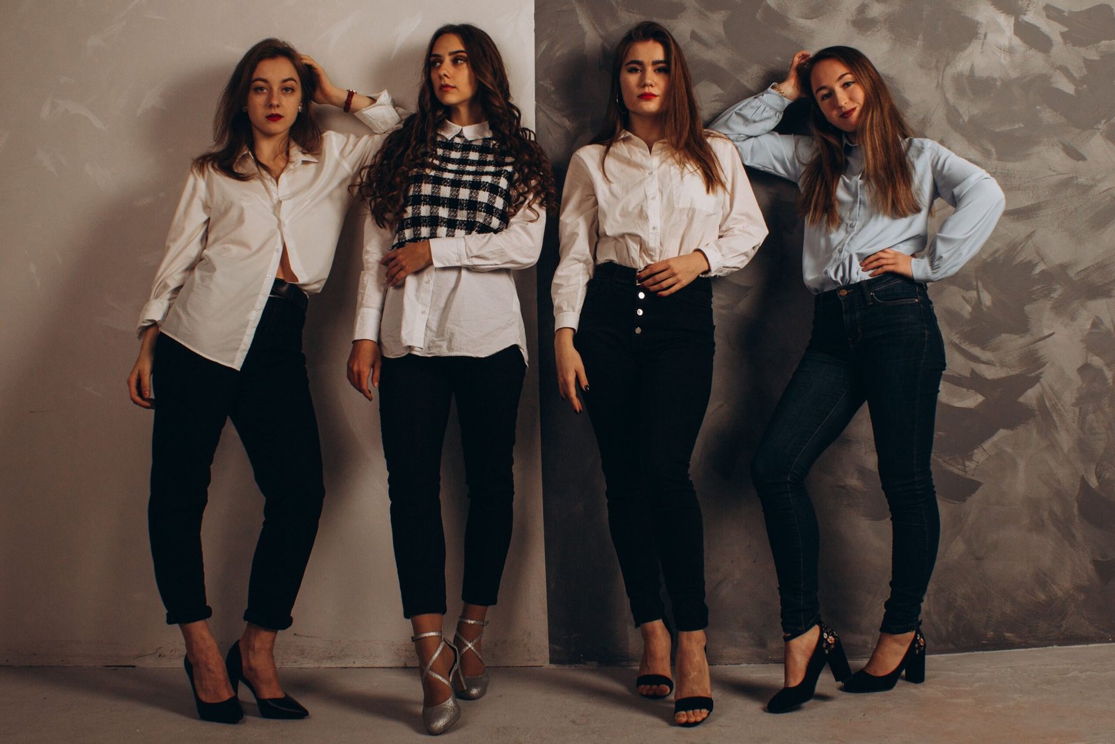 Home A group of fashionable women posing in a studio wearing smart casual outfits.